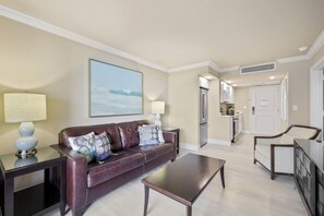 A living room with a leather sofa, a coffee table, and a painting on the wall.