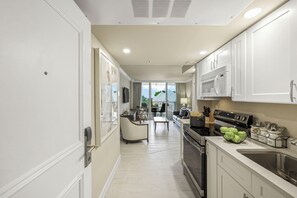 A modern kitchen with white cabinetry, a black stove, and a dining area with a table and chairs.