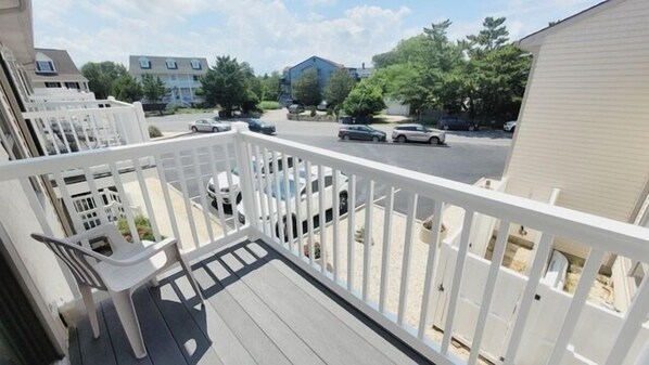 Een balkon met uitzicht op een parkeerplaats en omliggende gebouwen.