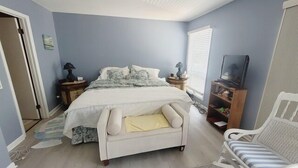 A bedroom with a bed, bedside tables, a TV stand, and a chair. - One block to the beach!  5 Rose Garden (Lewes)