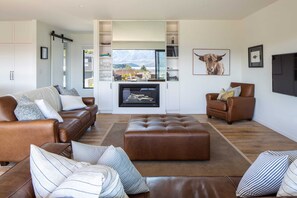 Una sala de estar moderna con sofás de cuero, un televisor de pantalla plana grande y una chimenea.
