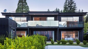 A modern two-story house with large glass windows, a balcony, and a satellite dish. - Waimaori Views The Sp (Wānaka)