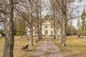 A pathway leading to a large building surrounded by trees.