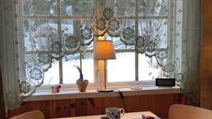 A wooden table with a laptop, a lamp, a potted plant, a muffin, a cup, and a teapot.
