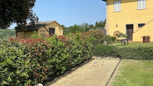 Un patio con césped, un pequeño jardín y un edificio amarillo con tejado de baldosas.