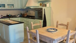 Eine Küche mit hellblauen Schränken, einem Holzespeisetisch mit Stühlen und einer Pendelleuchte.