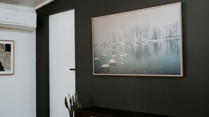 Fotografía enmarco de cisnes en un lago con árboles de fondo, colgada en una pared oscura.