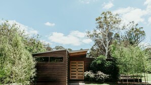 A wooden cabin with a sloped roof, surrounded by trees and a clear sky. - The Artemis Cottage - Romantic Couples Retreat (Woodlands)