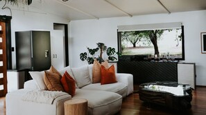 Una sala de estar moderna con un sofá, una mesita de centro y un ventanal con vistas a árboles.