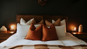 A neatly made bed with white and brown pillows, a wooden headboard, and bedside lamps.
