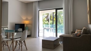 A modern living room with a sofa, a coffee table, a TV, and a dining area with chairs and a table.