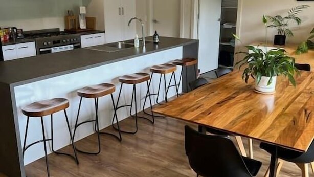 A modern kitchen with a central island, bar stools, and pendant lighting.