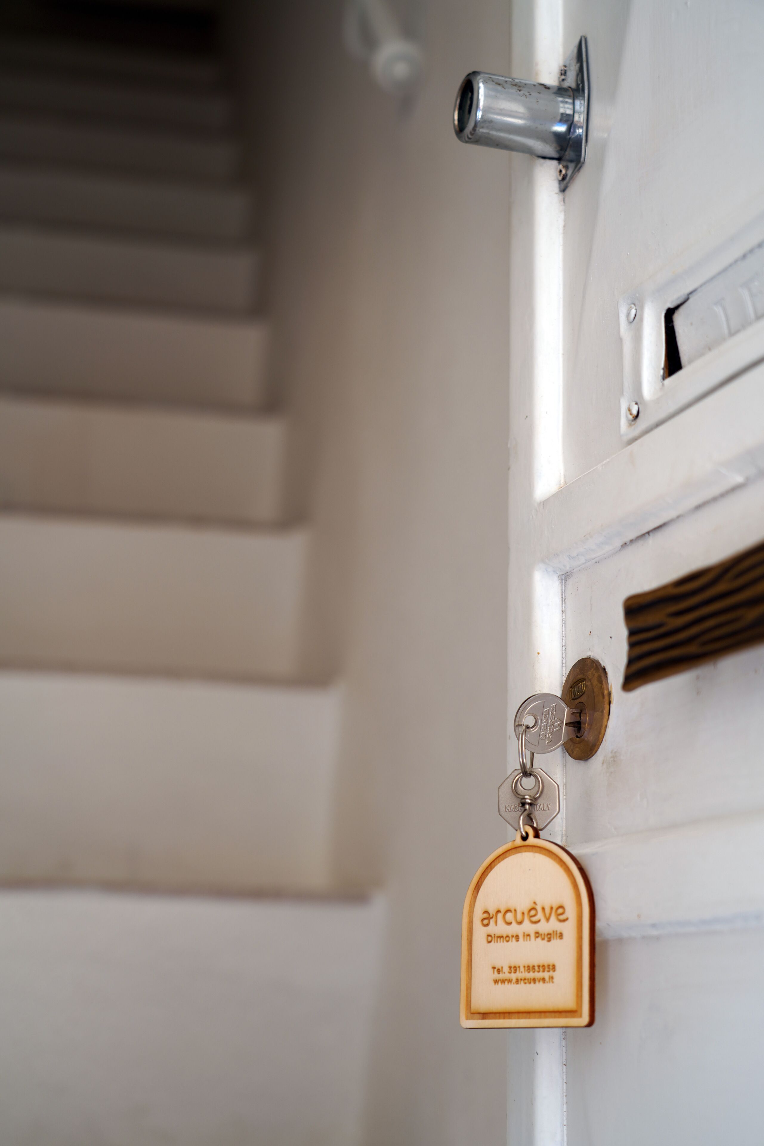 A door with a keyhole, a metal handle, and a wooden plaque with text.