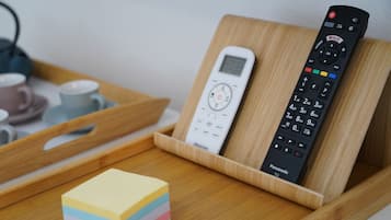 Een houten dienblad met een afstandsbediening, een plakkerige brief en een beker.