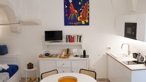 Un espacio habitable compacto con comedor, kitchenette y televisor montado en la pared.