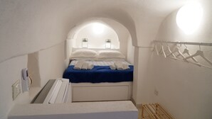 Un dormitorio pequeño y acogedor con una cama individual, un calentador integrado y un armario blanco.