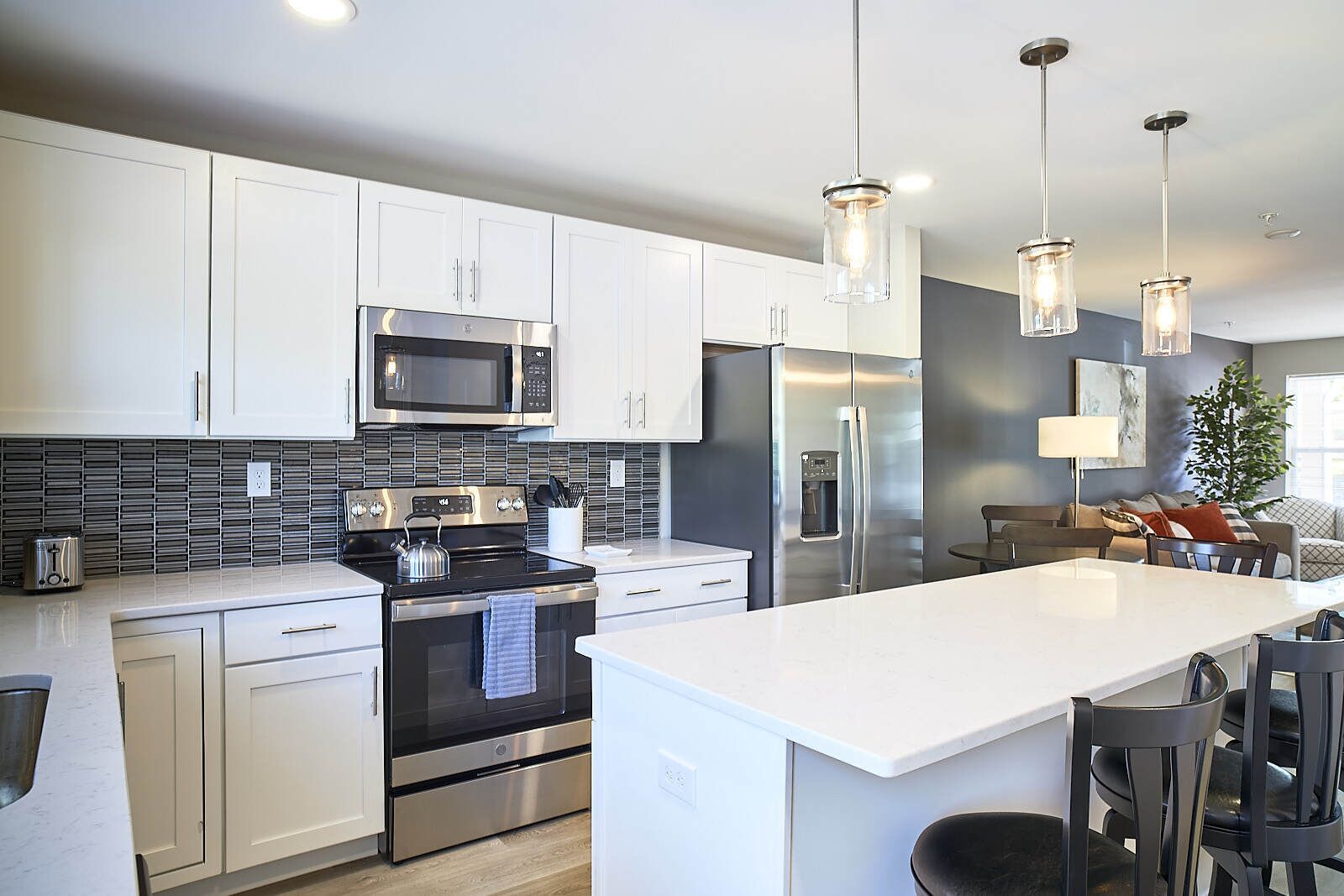A modern kitchen with stainless steel appliances, white cabinetry, and pendant lighting.