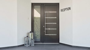 A reception area with a dark door, a wall-mounted sign, and two glass lanterns on the floor. - Lorelei Pension Adults Only (Gyenesdias)