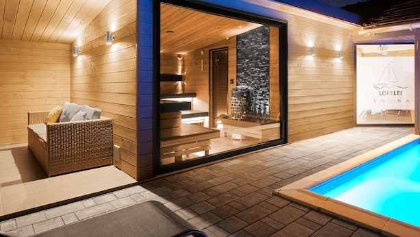 A modern spa with a wooden exterior, a glass door entrance, a wicker sofa, and a pool area. - Lorelei Pension Adults Only (Gyenesdias)
