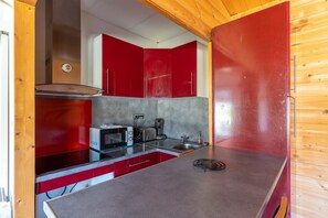 Une cuisine de taille réduite avec des placards rouges, un four à micro-ondes, un grille-pain et un évier.