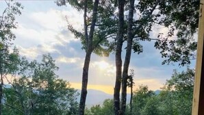 Una vasca idromassaggio con un molo in legno e vista su alberi e montagne sullo sfondo.