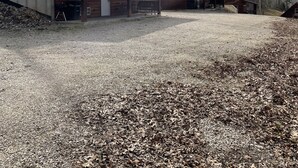 A rustic log cabin with a gravel driveway and surrounding trees. - Cozy Cabin on the edge of town only 1/2 mile from Current River ! (Van Buren)