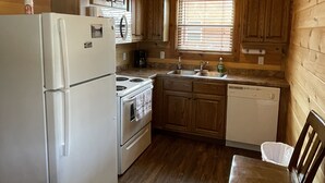 A compact kitchen with wooden cabinets, a refrigerator, stove, and a dishwasher. - Cozy Cabin on the edge of town only 1/2 mile from Current River ! (Van Buren)