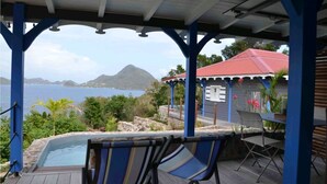 A covered outdoor area with a pool, lounge chairs, and a view of the sea and mountains. - Cases créoles classified 4**** with private pools (Terre-de-Bas)