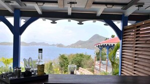 A bar area with a view of the sea and mountains, featuring a bottle of rum, glasses, and a tray. - Cases créoles classified 4**** with private pools (Terre-de-Bas)