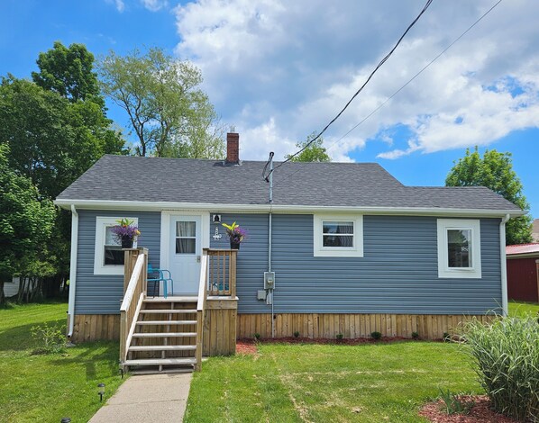 A two-story house with a front porch, a wooden staircase, and a small front yard.