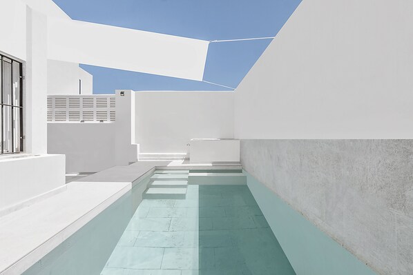 Un espace architectural moderne doté d’une piscine, de murs blancs et d’une verrière.