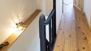 A wooden staircase with a black handrail leading to a landing.
