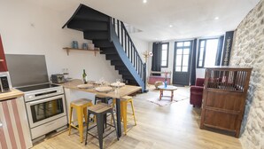 A modern kitchen with a central island, a built-in oven, and a black staircase leading to an upper level.
