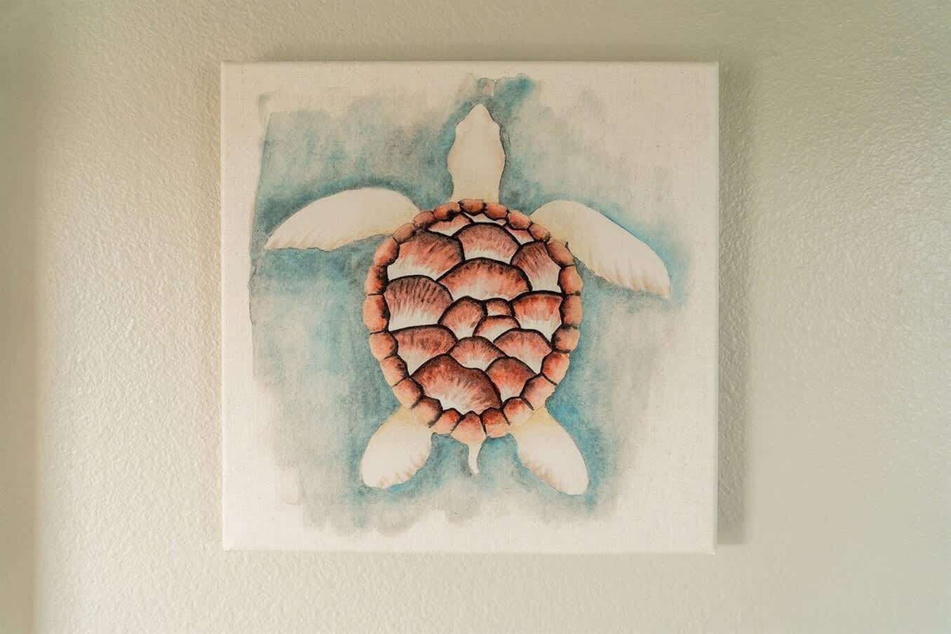 A square painting of a turtle on a white wall.