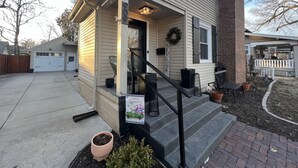 A single-story house with a front porch, a garage, and a brick chimney. - Remodeled Riverside Cottage w/sunroom, She-shed. Walk to golf, tennis, Botanica, (Wichita)