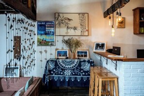 A traditional interior with a wooden table, hanging decorations, and framed artwork on the walls. - Perch House (Dali City)