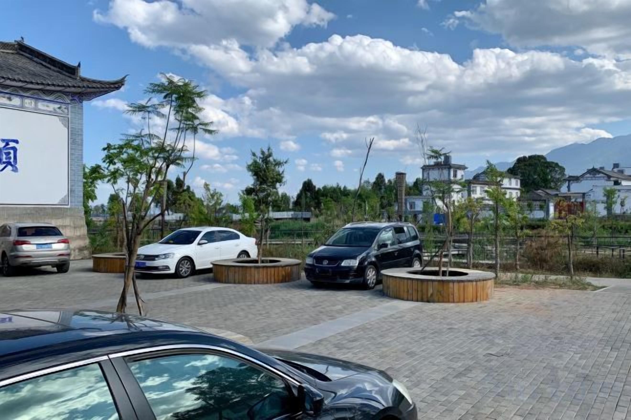 Un estacionamiento con coches, un edificio con un letrero y árboles.