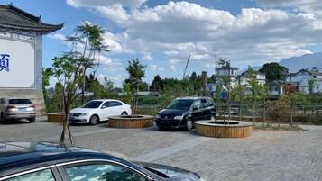 Un estacionamiento con coches, un edificio con un letrero y árboles.