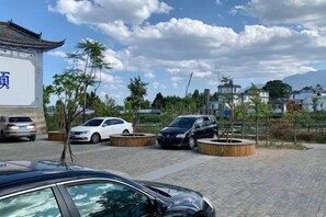 Un estacionamiento con coches, un edificio con un letrero y árboles.