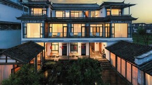 A traditional Chinese-style building with multiple levels, large windows, and a courtyard with a water feature. - Perch House (Dali City)