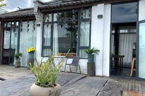 A traditional-style building with large windows, a wooden deck, and potted plants. - Perch House (Dali City)