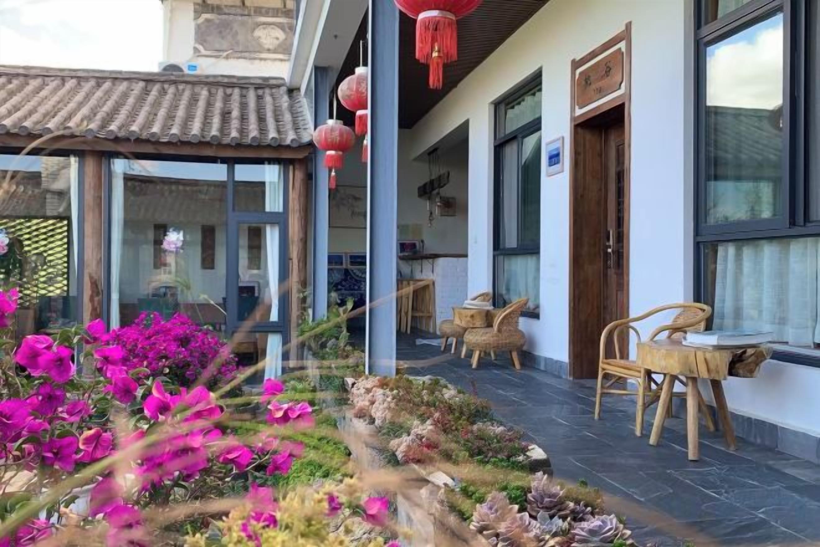 Een traditioneel gebouw in Chinese stijl met een tuin, houten meubels en rode lantaarns.