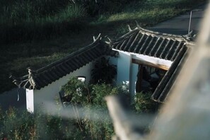 A traditional building with a curved roof, surrounded by vegetation. - Perch House (Dali City)
