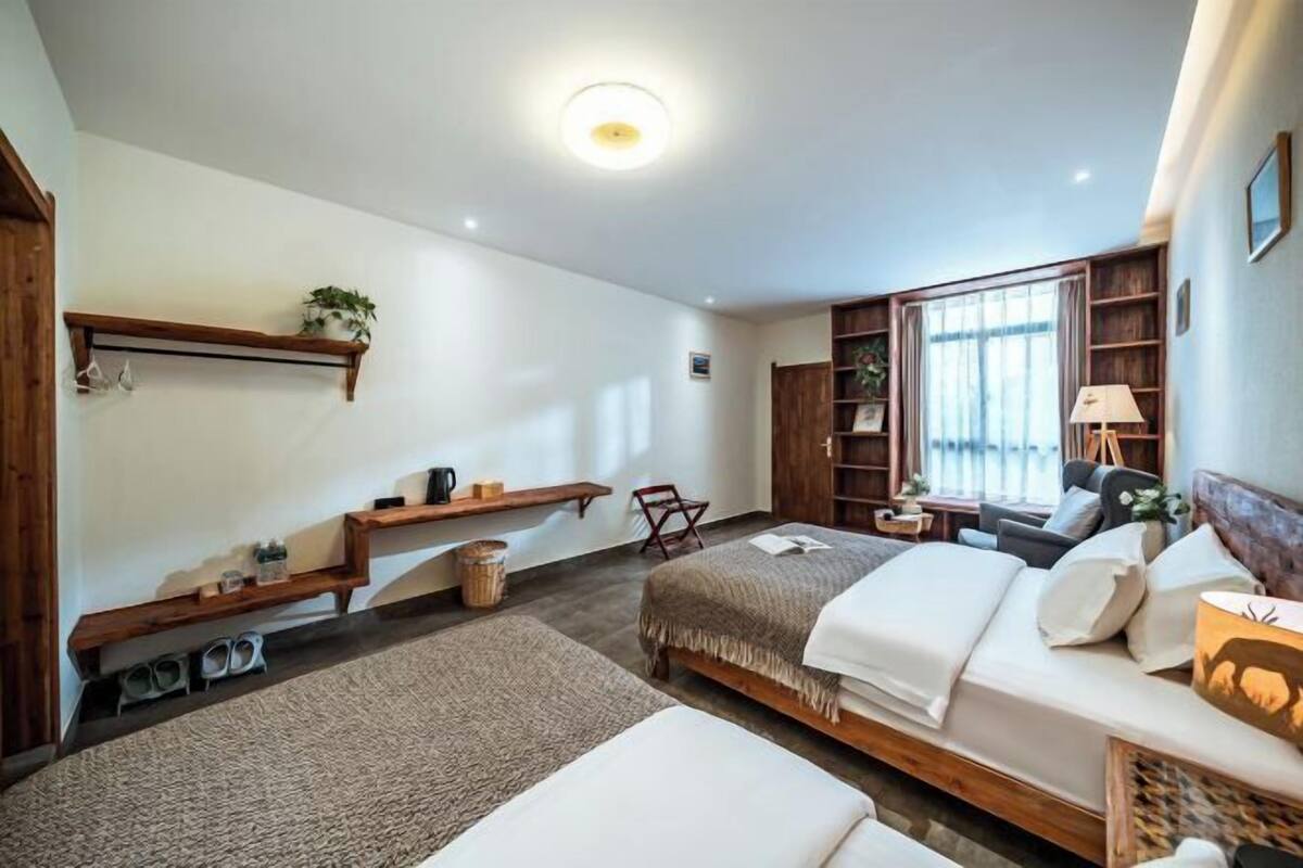 A bedroom with a bed, a chair, a small table, and a shelf with a plant.