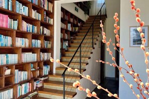 Una escalera conduce a una plataforma con una estantería llena de libros.