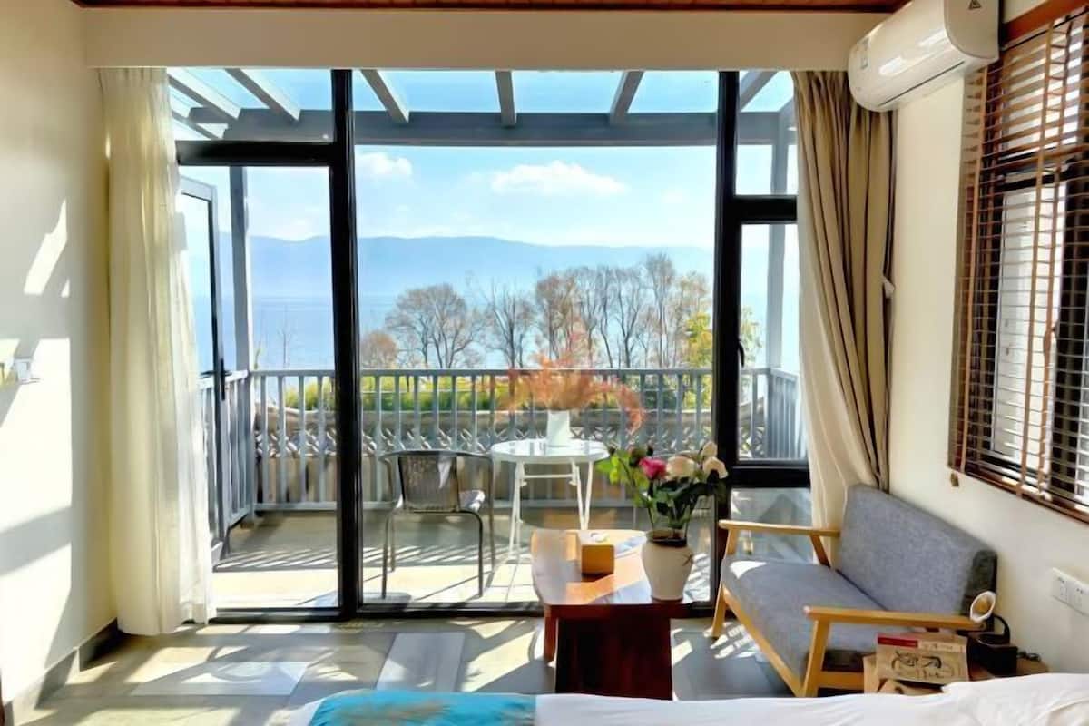 A room with a balcony, a sofa, a table, and a bed.