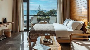 A hotel room with a bed, a desk, a chair, a small table with a tray, and a view of the outdoors. - Perch House (Dali City)