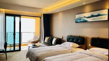 Quarto de hotel com duas camas, uma cadeira, uma mesinha e uma janela grande com vista.