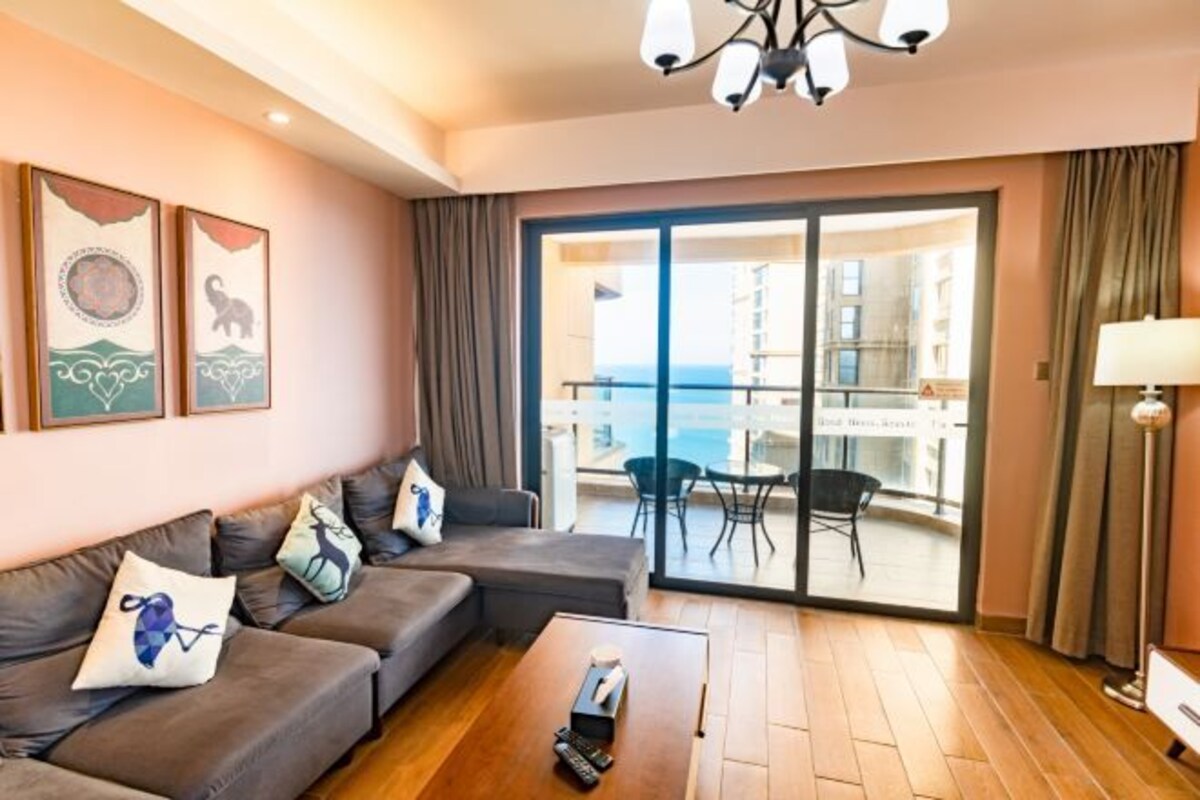 A modern living room with a sofa, a coffee table, and a balcony with a view.