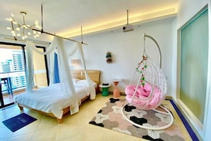 A modern bedroom with a bed, a hanging chair, a small table, and a projector on the ceiling. - Good Time Seaview Hotel (Huidong)